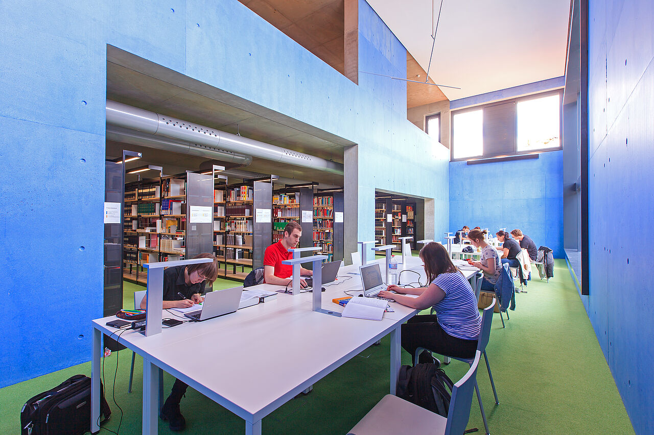 Menschen arbeiten in einer Bibliothek und sitzen am Tisch