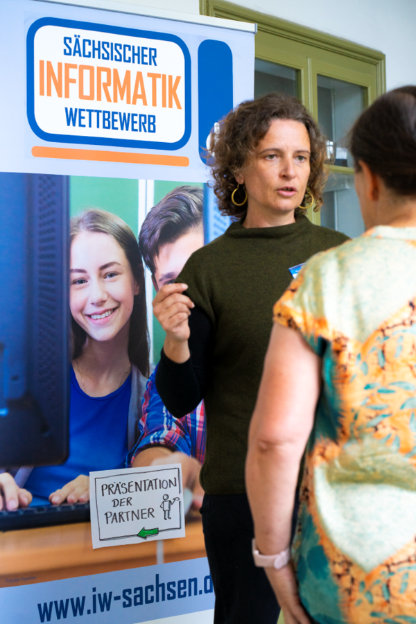 Frau vor einem Bild im Gespräch mit einer Person 