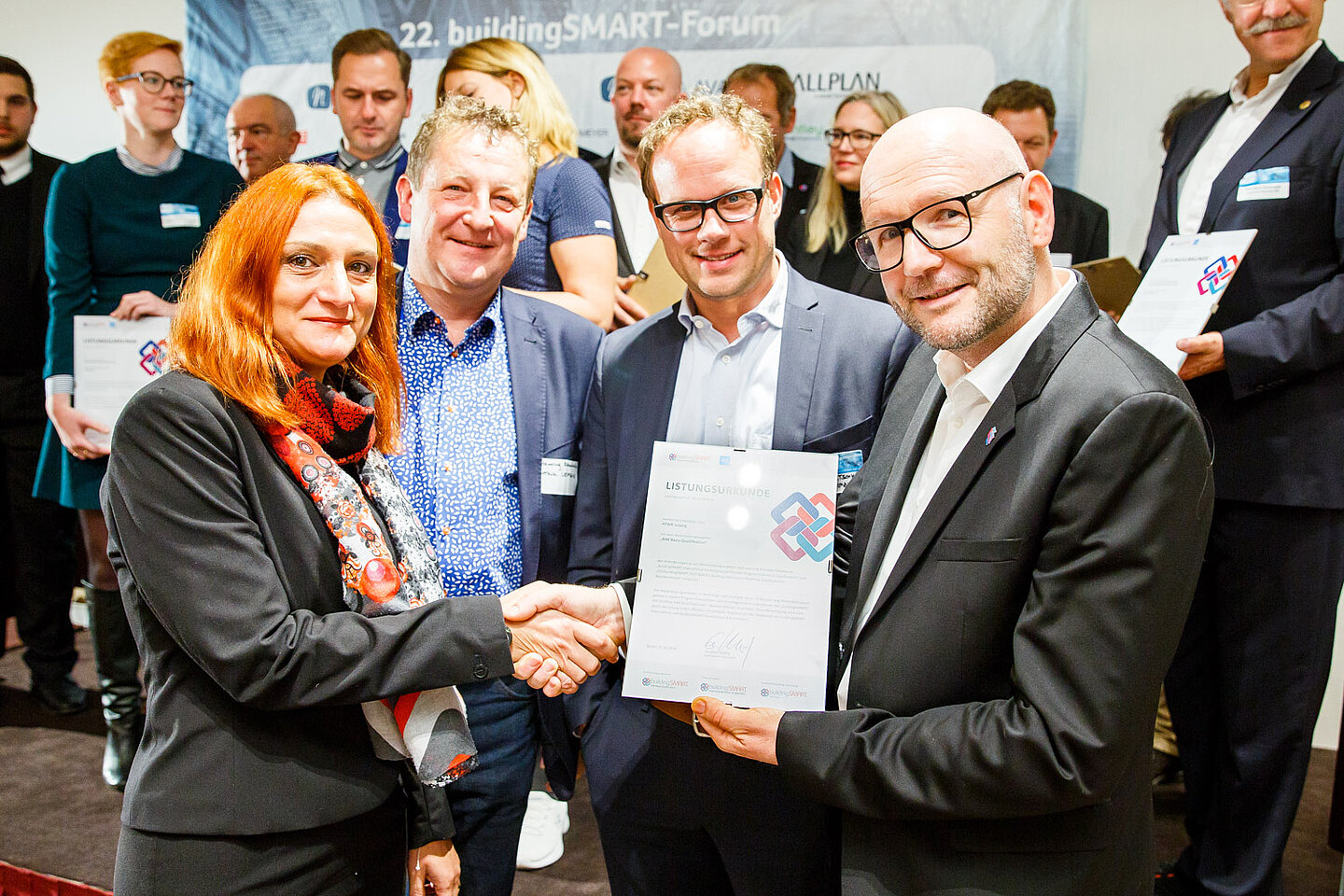 Prof. Dr. Monica Rossi, Prof. Henning Rambow und Timo Kretschmer (v.l.) von der HTWK Leipzig nehmen die Listungsurkunde in Empfang. Ganz rechts: Gunther Wölfle, Geschäftsführer buildingSMART Deutschland. (Foto: buildingSMART Deutschland) Prof. Dr. Monica Rossi, Prof. Henning Rambow und Timo Kretschmer (v.l.) von der HTWK Leipzig nehmen die Listungsurkunde in Empfang. Ganz rechts: Gunther Wölfle, Geschäftsführer buildingSMART Deutschland. (Foto: buildingSMART Deutschland)