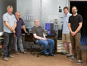 5 Männer stehen vor der Absorberkammer und vor Computern