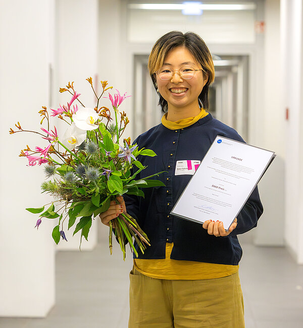 Mako Fukuda wurde mit dem DAAD-Preis ausgezeichnet. (Foto: Swen Reichhold/HTWK Leipzig) junge Japanerin mit Blumen und Urkunde